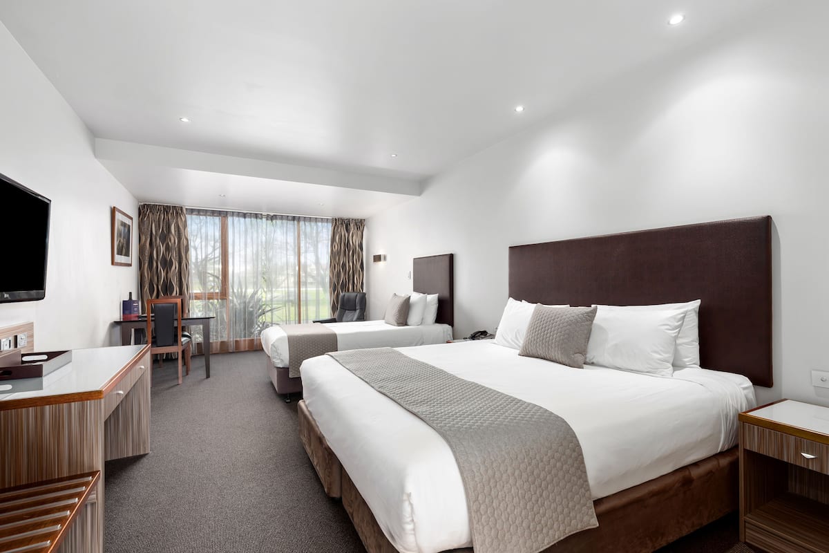Une chambre d’hôtel avec deux lits, un bureau, une chaise et un téléviseur.
