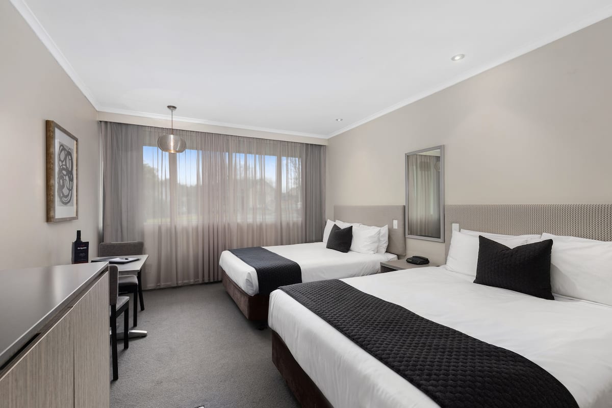 Une chambre d’hôtel avec deux lits, un bureau et une chaise.