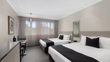 A hotel room with two beds, a desk, and a chair.
