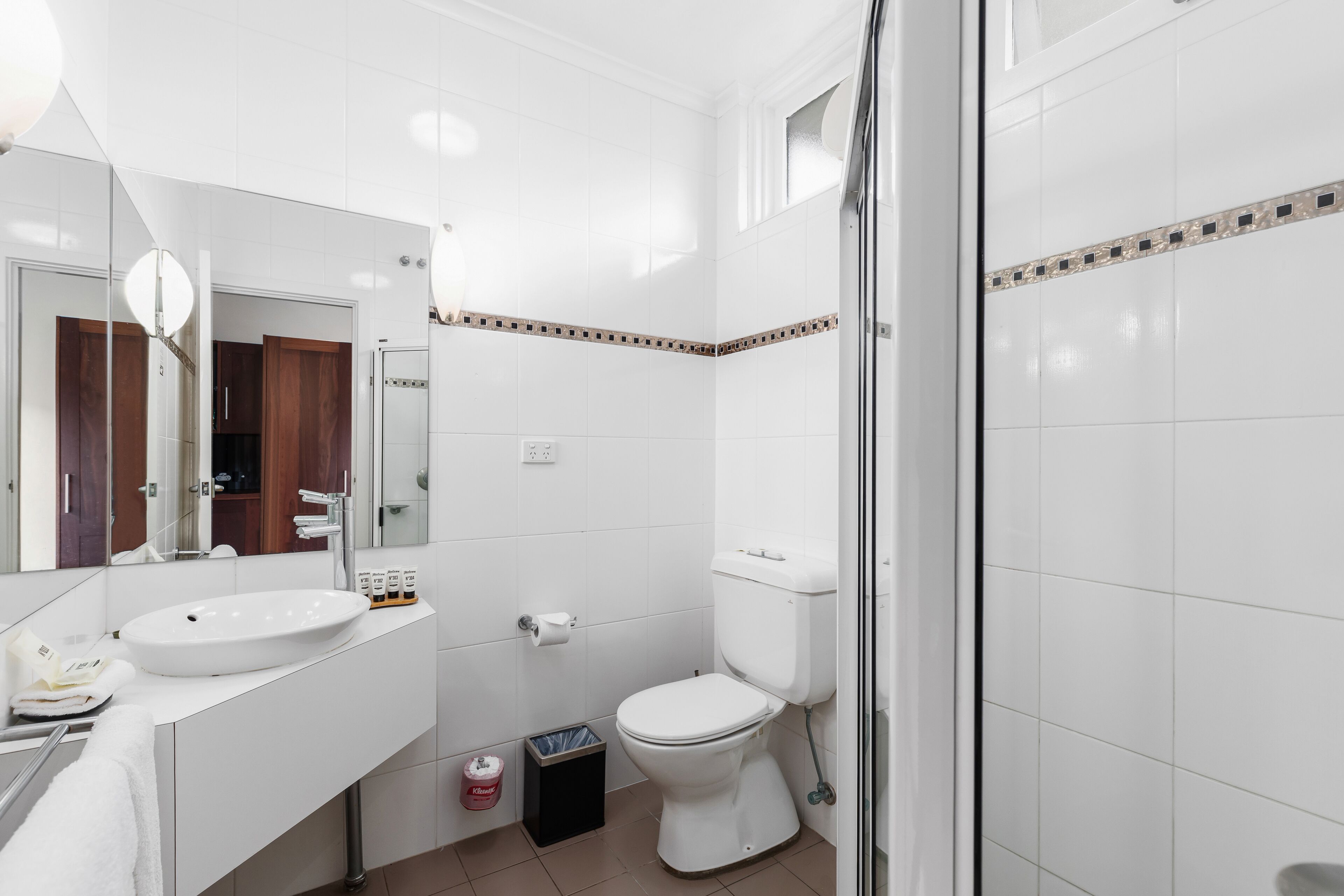 A modern bathroom with a white sink, toilet, and shower.
