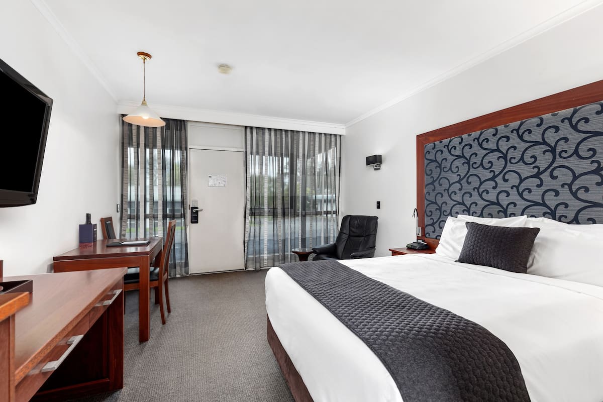 Une chambre d’hôtel avec un grand lit, un bureau, une chaise, une télévision et une vue par la fenêtre.
