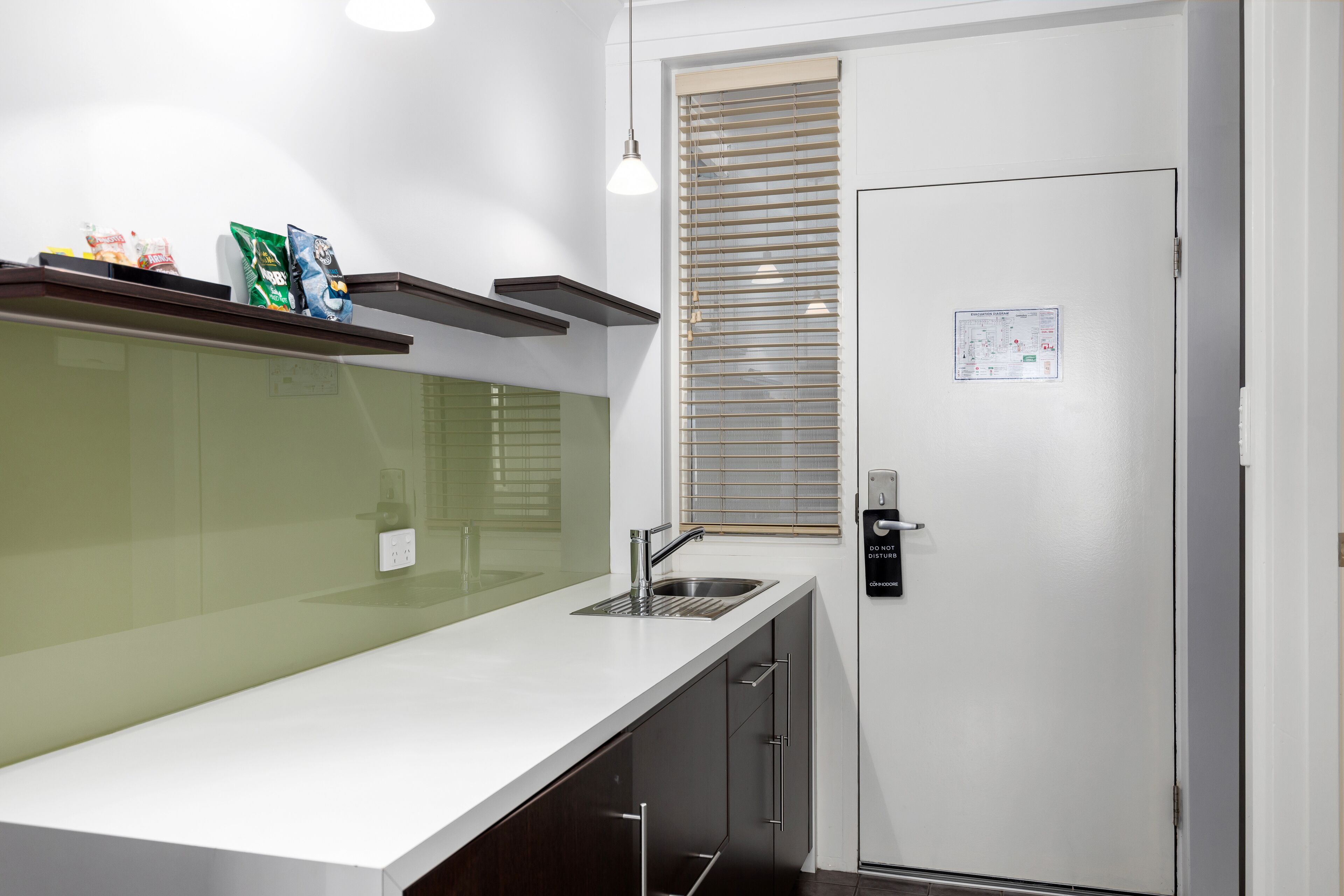 A modern kitchen with a white countertop, stainless steel sink, and a built-in oven.
