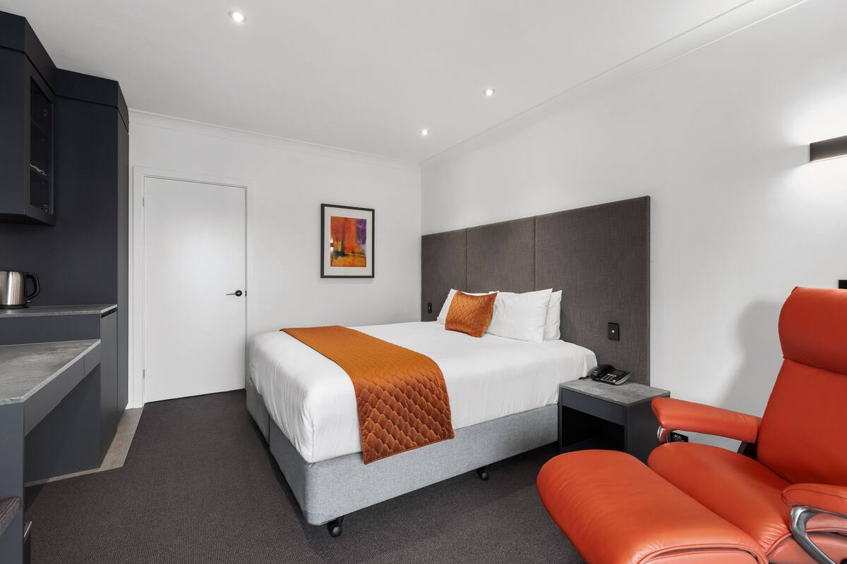 Une chambre d’hôtel moderne, équipée d’un lit, d’un bureau, d’une chaise et d’un tableau au mur.