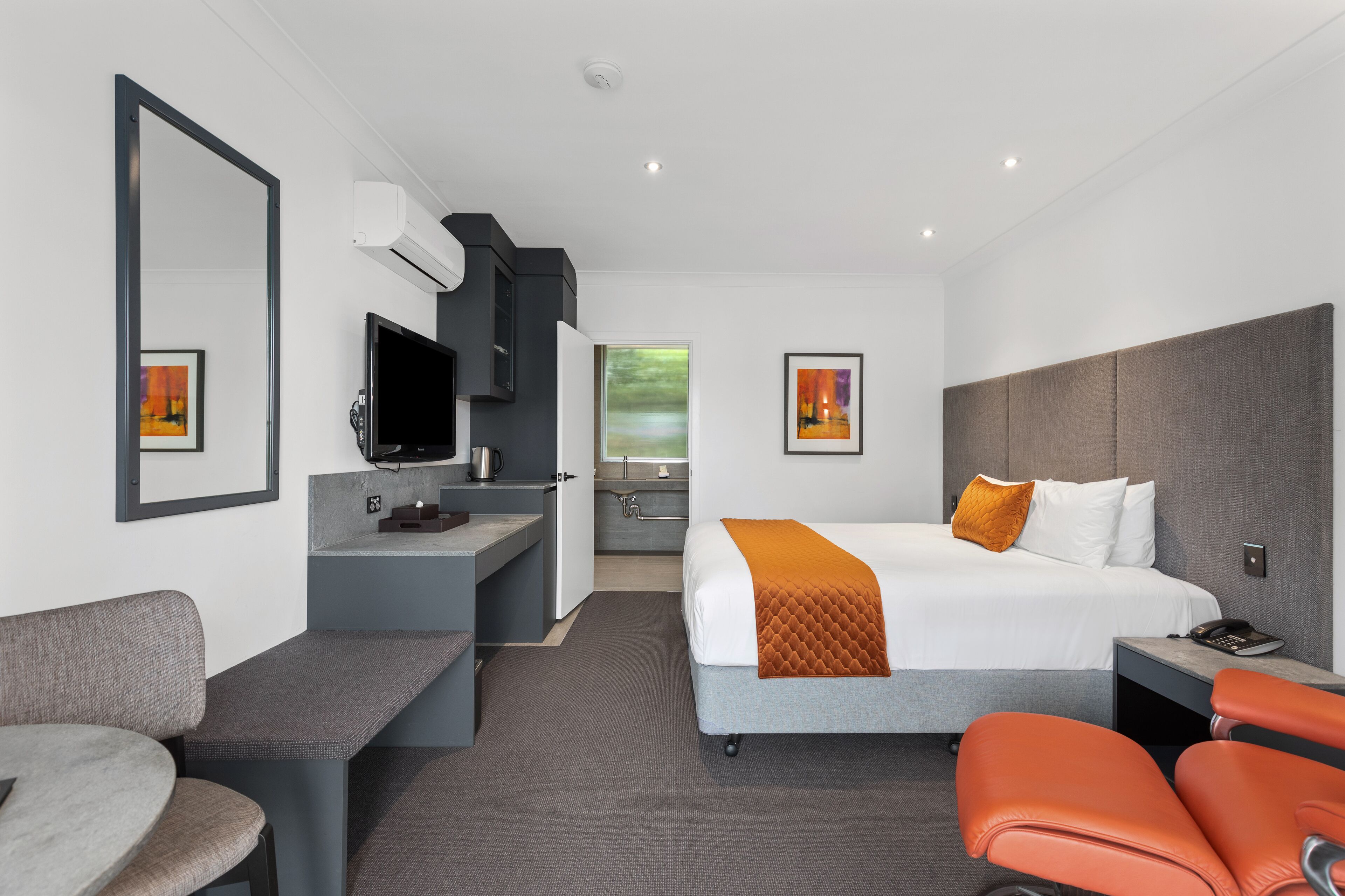 A modern hotel room with a large bed, a desk, a chair, and a television.