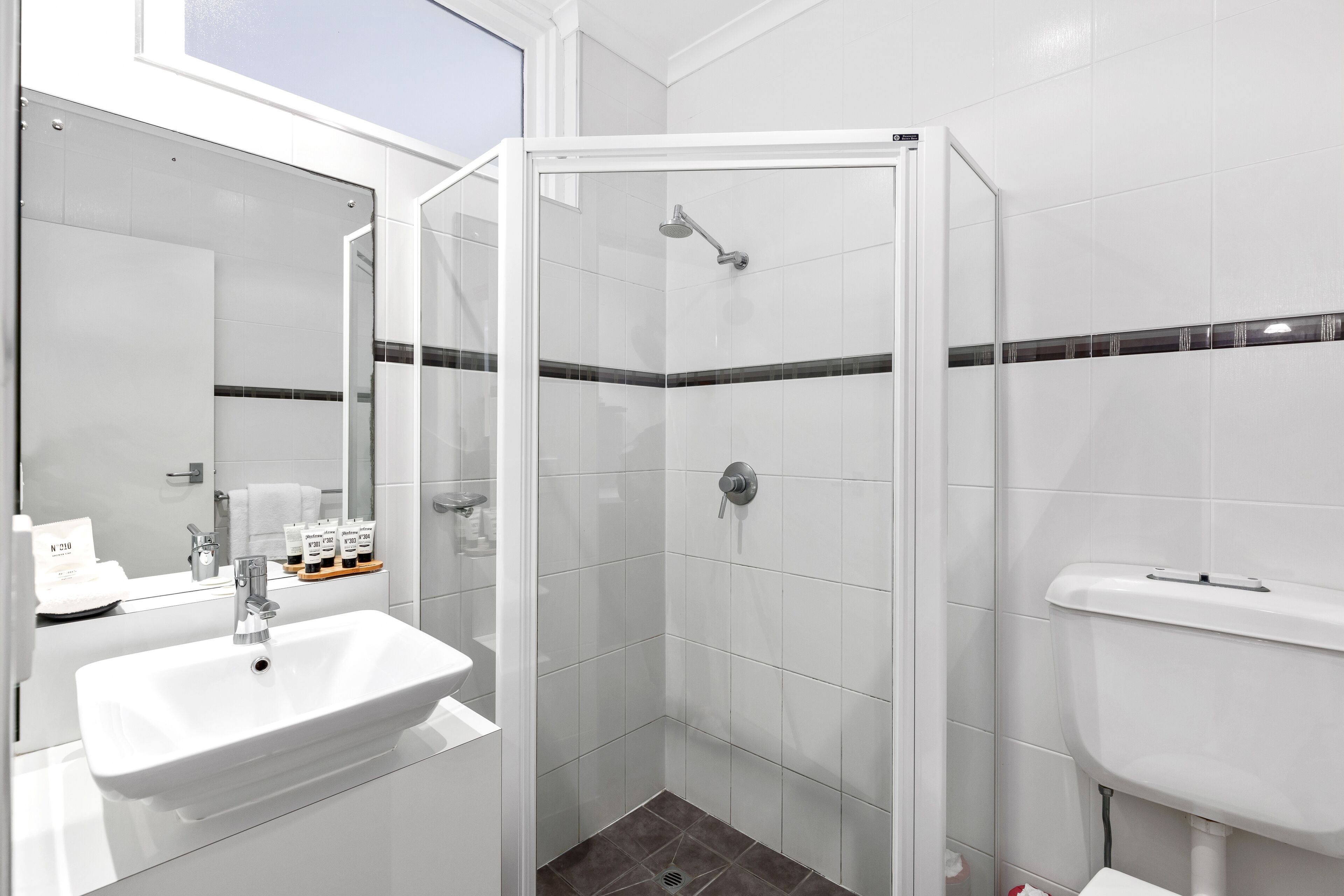 Un baño moderno con ducha envuelta en vidrio, un lavabo blanco y un inodoro.
