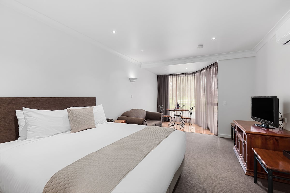 Une chambre d’hôtel avec un grand lit, une télévision, un bureau et un coin salon agrémenté de rideaux.