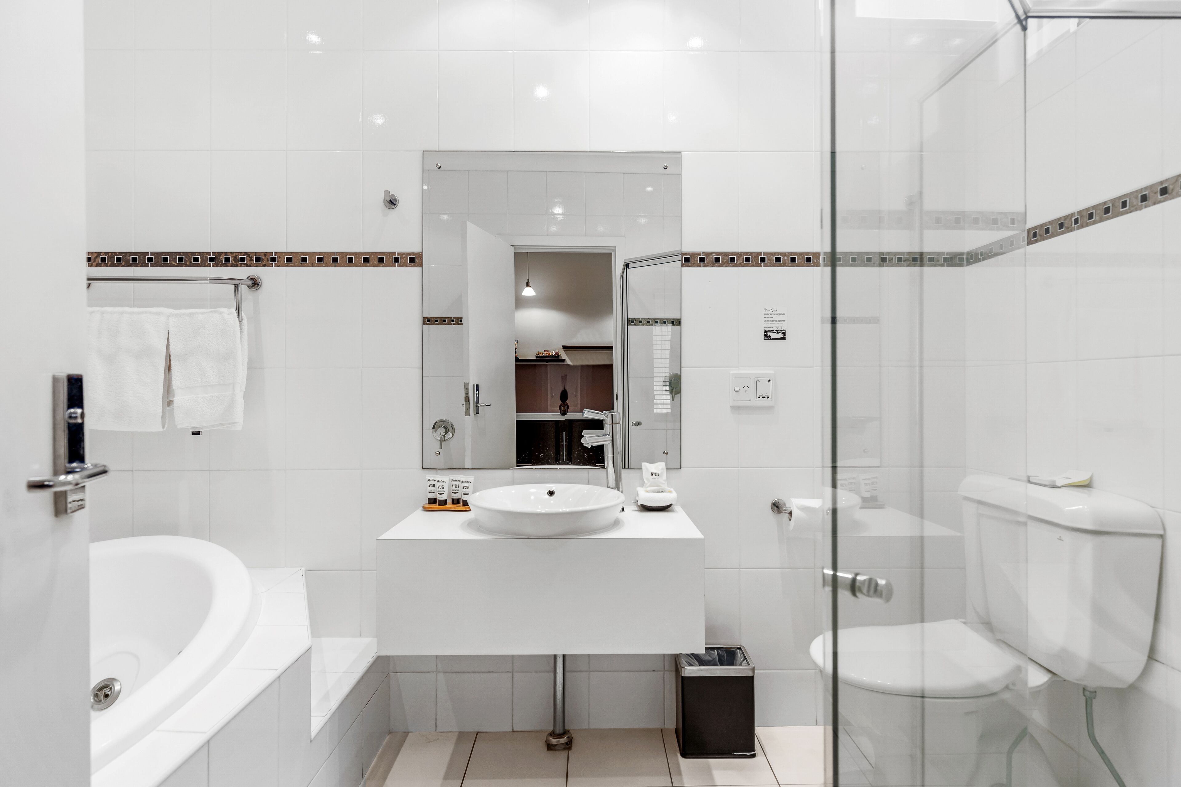 A modern bathroom with a white sink, mirror, and bathtub.