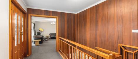 A hallway with wooden paneling, a carpeted floor, and a wooden railing.