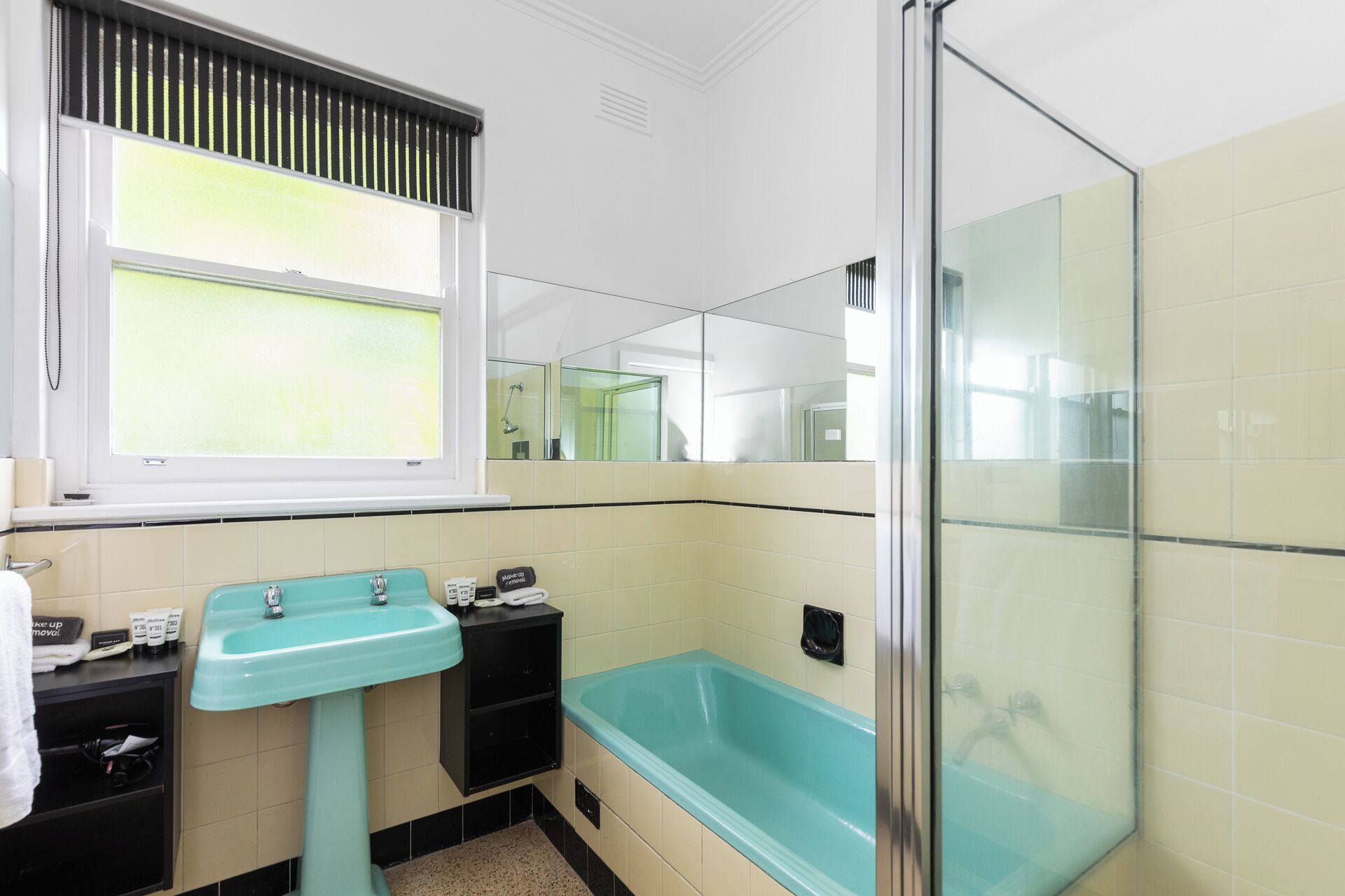 A bathroom with a turquoise sink, a bathtub, and a shower area.