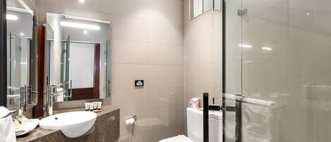 A modern bathroom with a sink, mirror, toilet, and glass shower enclosure.