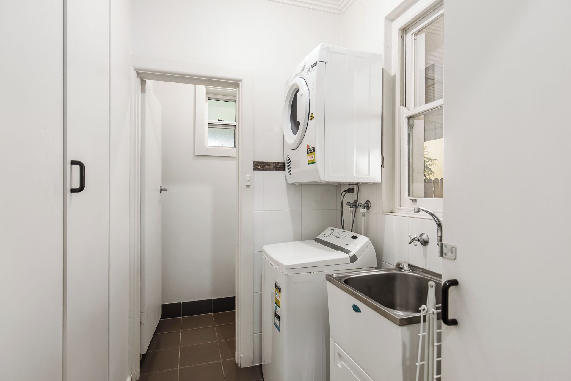 A laundry area with a washing machine, a dryer, and a sink.