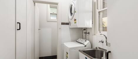A laundry area with a washing machine, a dryer, and a sink.