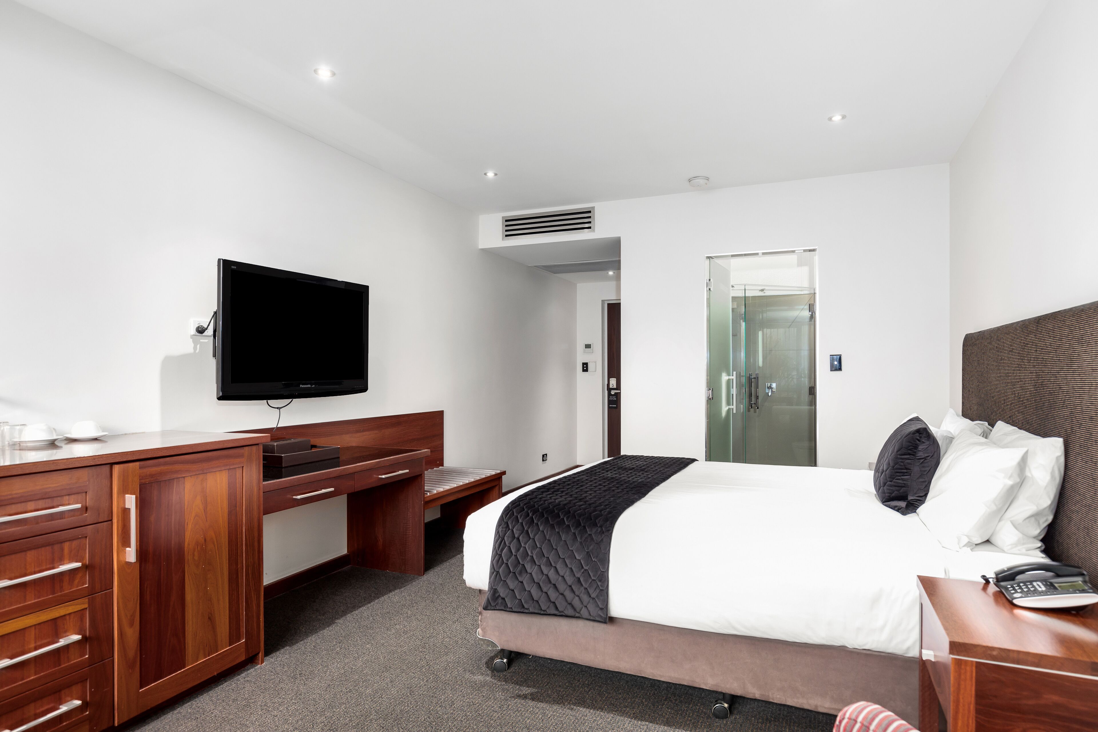 Une chambre d’hôtel avec un lit, un bureau, une télévision et une porte de salle de bain.