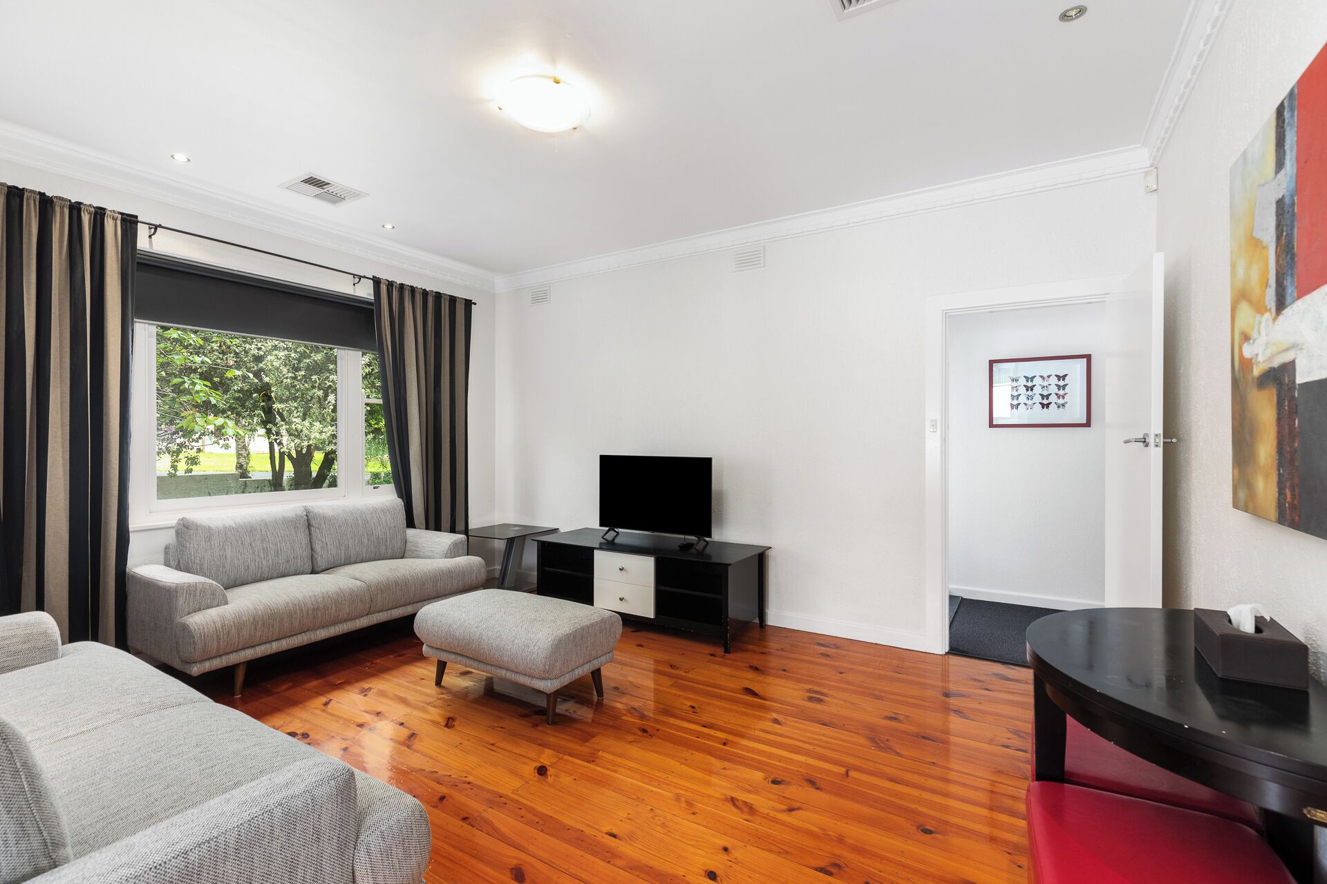 Een moderne woonkamer met een bank, een poef en een flatscreen televisie op een dressoir.
