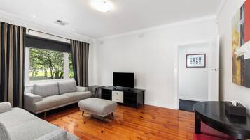 Een moderne woonkamer met een bank, een poef en een flatscreen televisie op een dressoir.