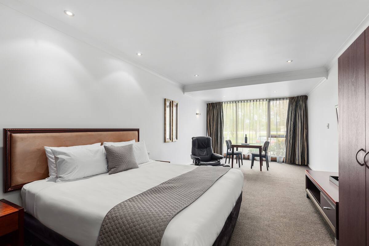 Une chambre d’hôtel avec un grand lit, un bureau et une chaise.