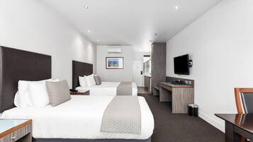 Een hotelkamer met twee bedden, een bureau, een televisie en een prullenbak.