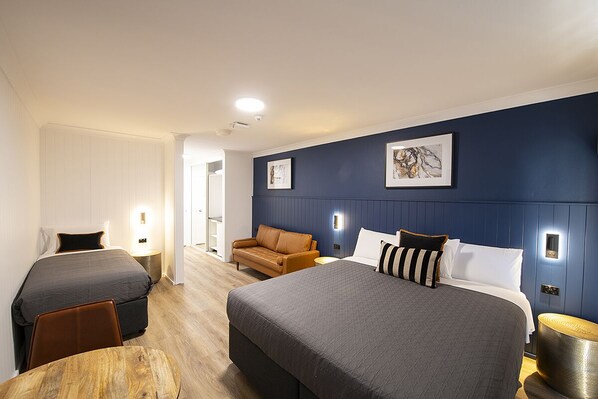 A hotel room with two beds, a sofa, and a dining table. - Southend Hotel (Maroubra)