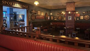 A sports lounge with a bar area, seating, and various framed memorabilia on the walls. - Southend Hotel (Maroubra)