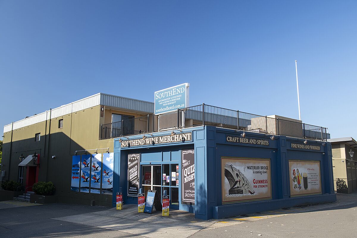A Southend Wine Merchant building with a blue facade, featuring a signboard and advertisements for events and products.