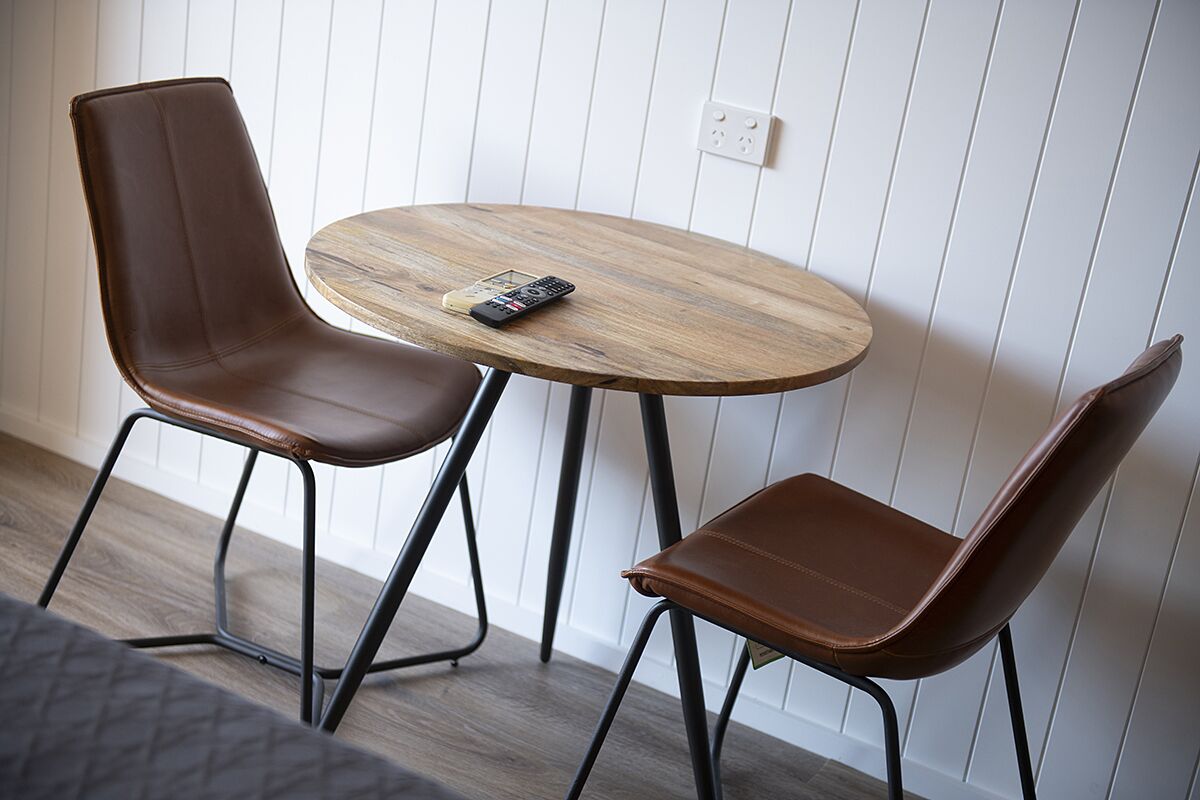 Comedor con dos sillones de cuero marrón y una mesa redonda de madera.