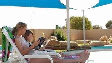 Una piscina al aire libre, sillones reclinables de piscina