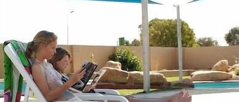 Una piscina al aire libre, sillones reclinables de piscina