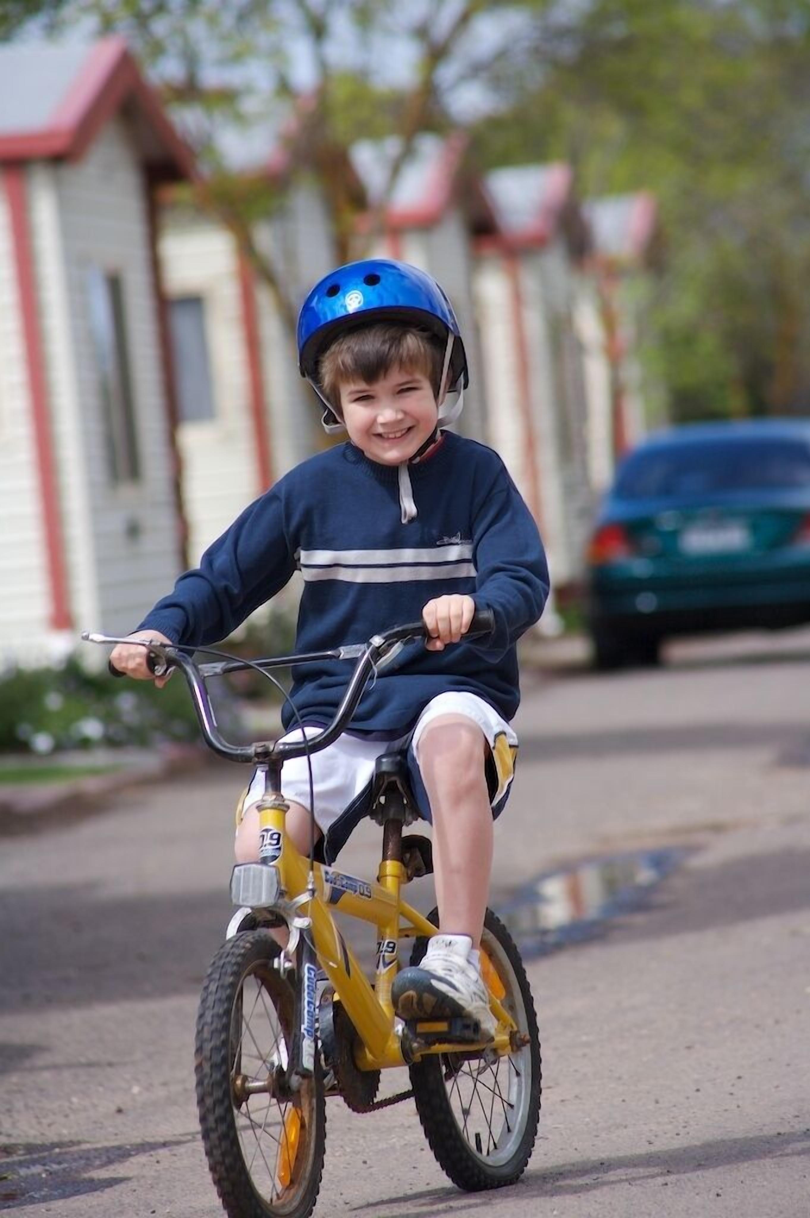 A child riding a yellow bicycle on a residential street.