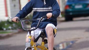 A child riding a yellow bicycle on a residential street.