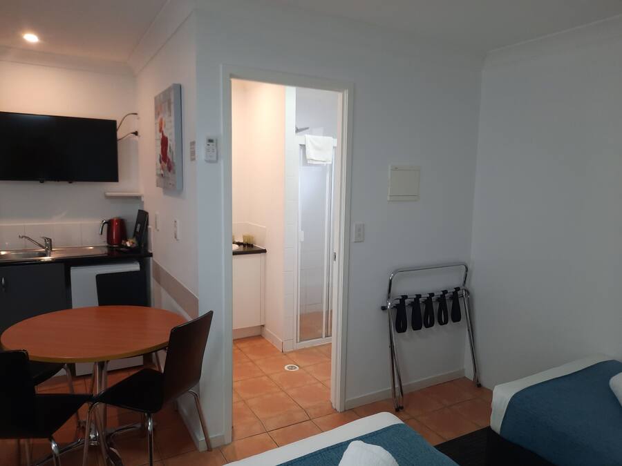 Un espacio habitable compacto con kitchenette, zona de comedor y cama.
