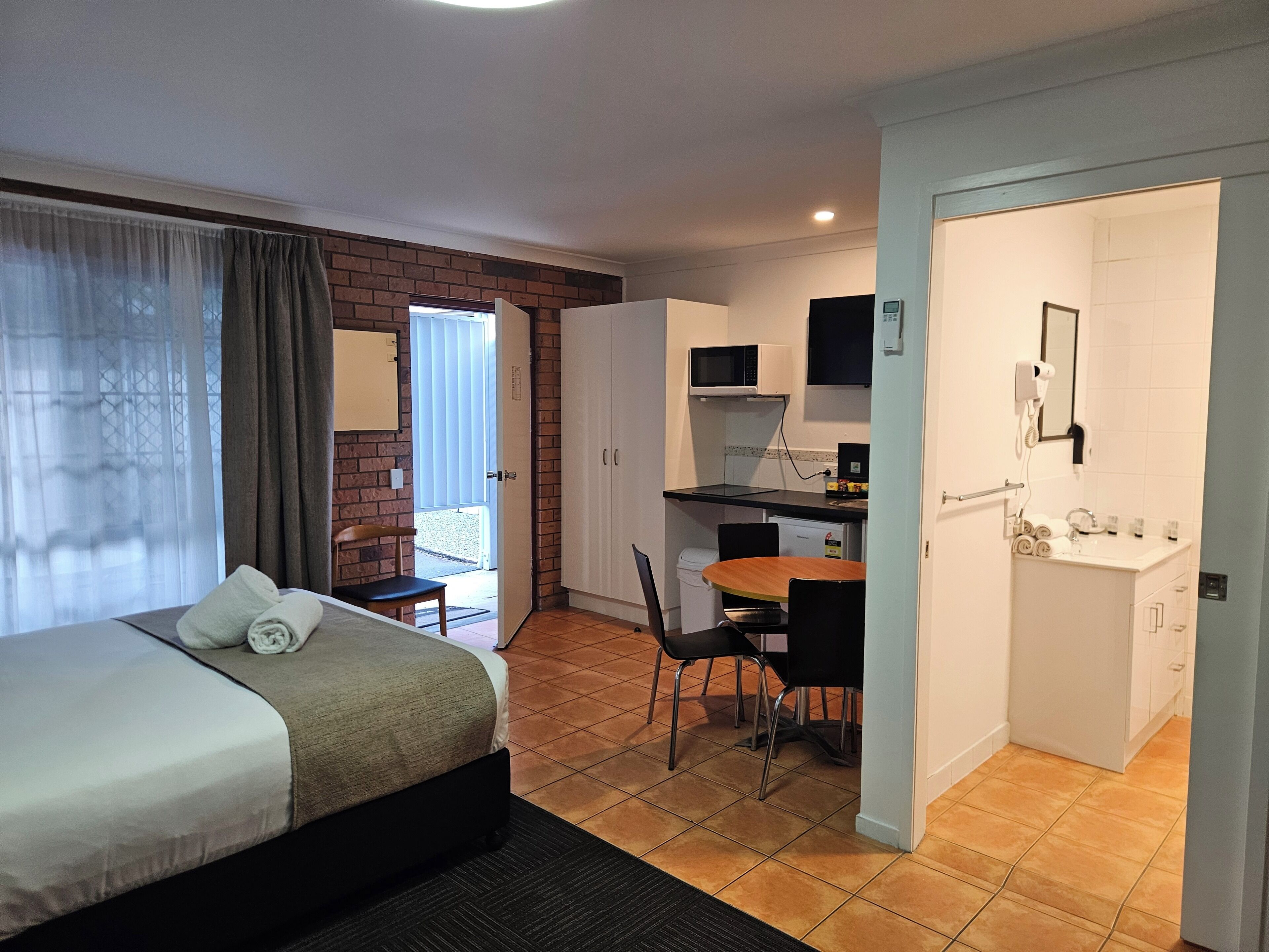 Hotelkamer met een bed, bureau, stoel, magnetron, föhn en wastafel.