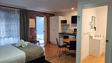 Hotelkamer met een bed, bureau, stoel, magnetron, föhn en wastafel.