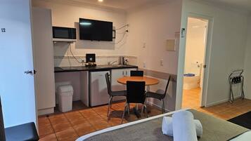 A compact hotel room with a kitchenette, a dining area, and a bathroom.