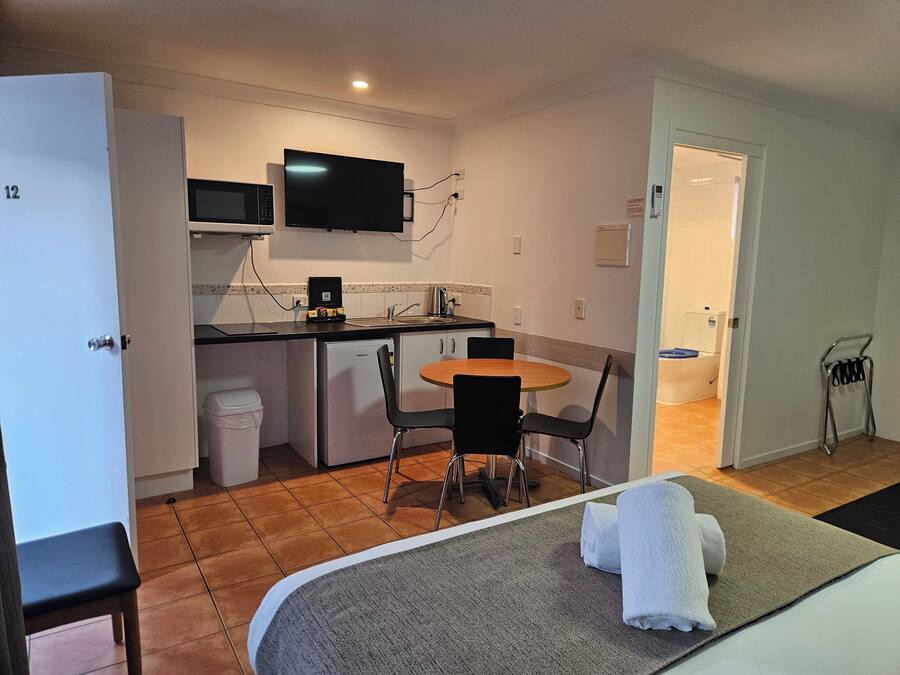 A compact hotel room with a kitchenette, a dining area, and a bathroom.