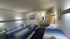 Ein Hotelzimmer mit zwei Betten, einem kleinen Badezimmer und einem Spiegel.