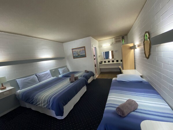 A hotel room with two beds, a small bathroom, and a mirror.