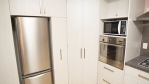 Eine Küche mit einem Edelstahl-Kühlschrank, einer Mikrowelle und einem Backofen.