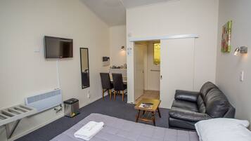 Una habitación de hotel con cama, televisión, escritorio y silla.