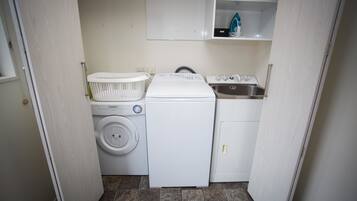 A compact laundry area with a washing machine, dryer, and a small sink.