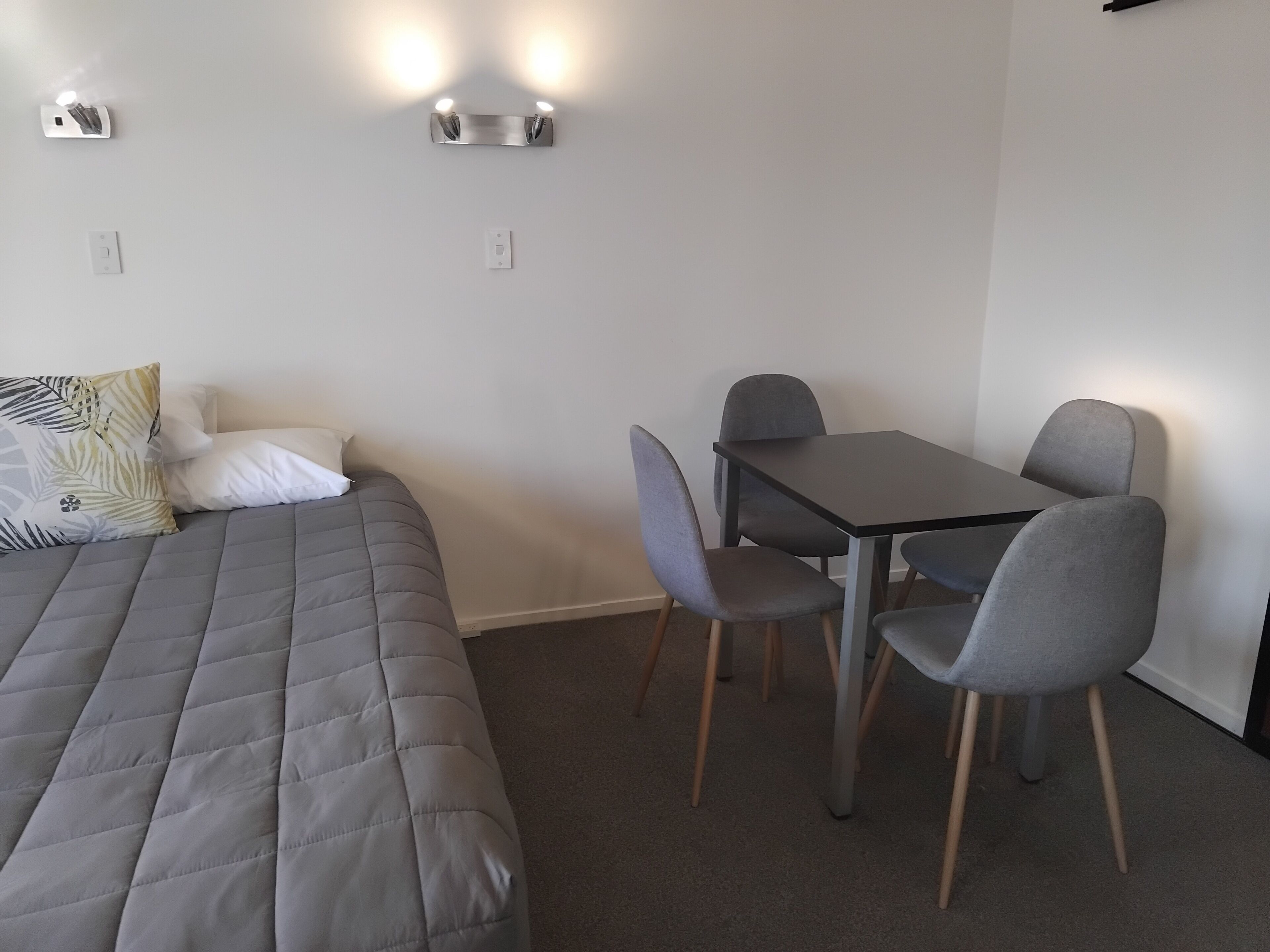 Un dormitorio con cama, mesita de noche y dos lámparas de pared.