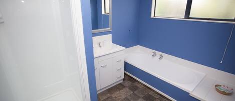 A bathroom with a white bathtub, a white sink, and a shower.