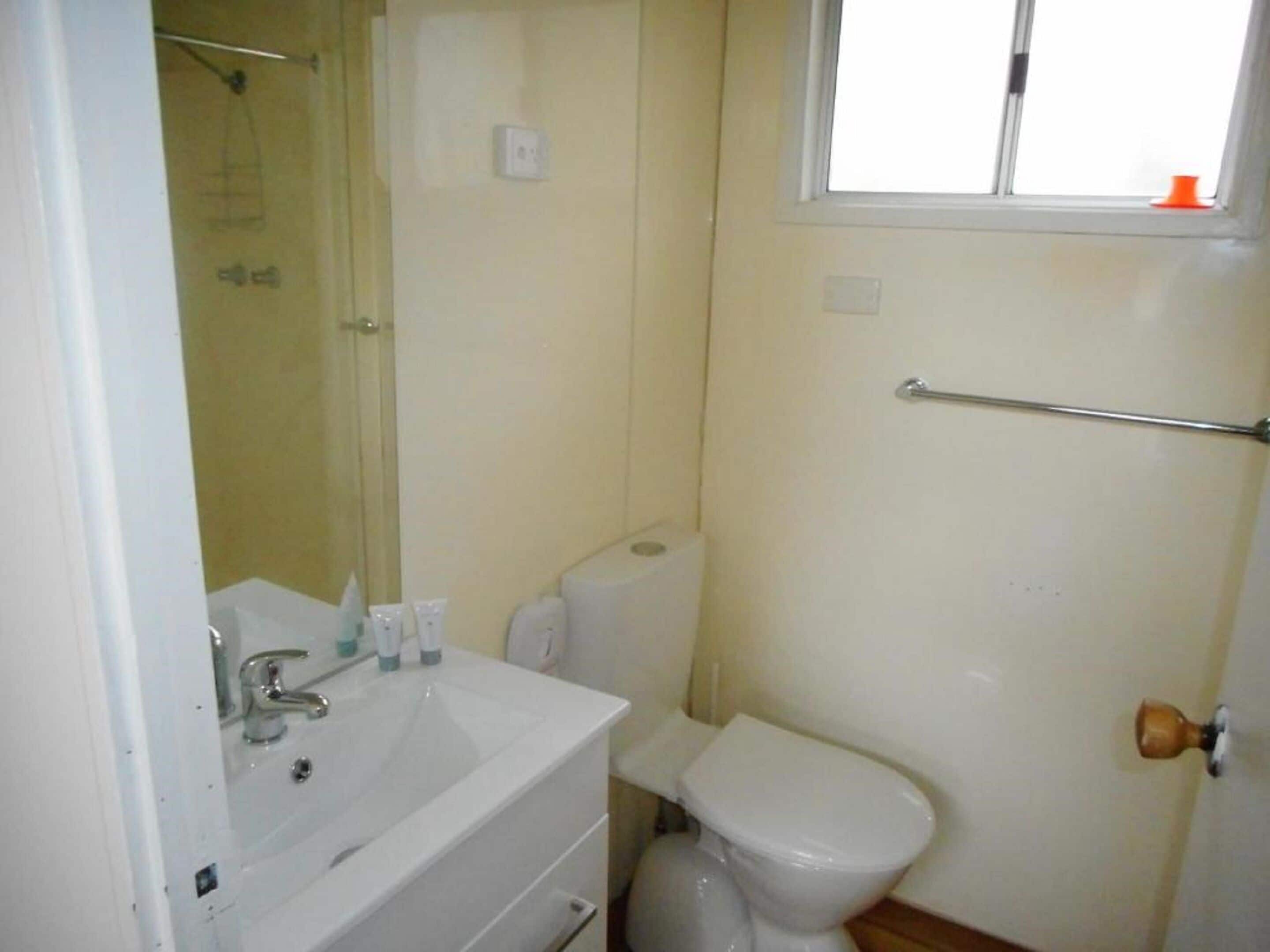 A bathroom with a sink, toilet, and a window.