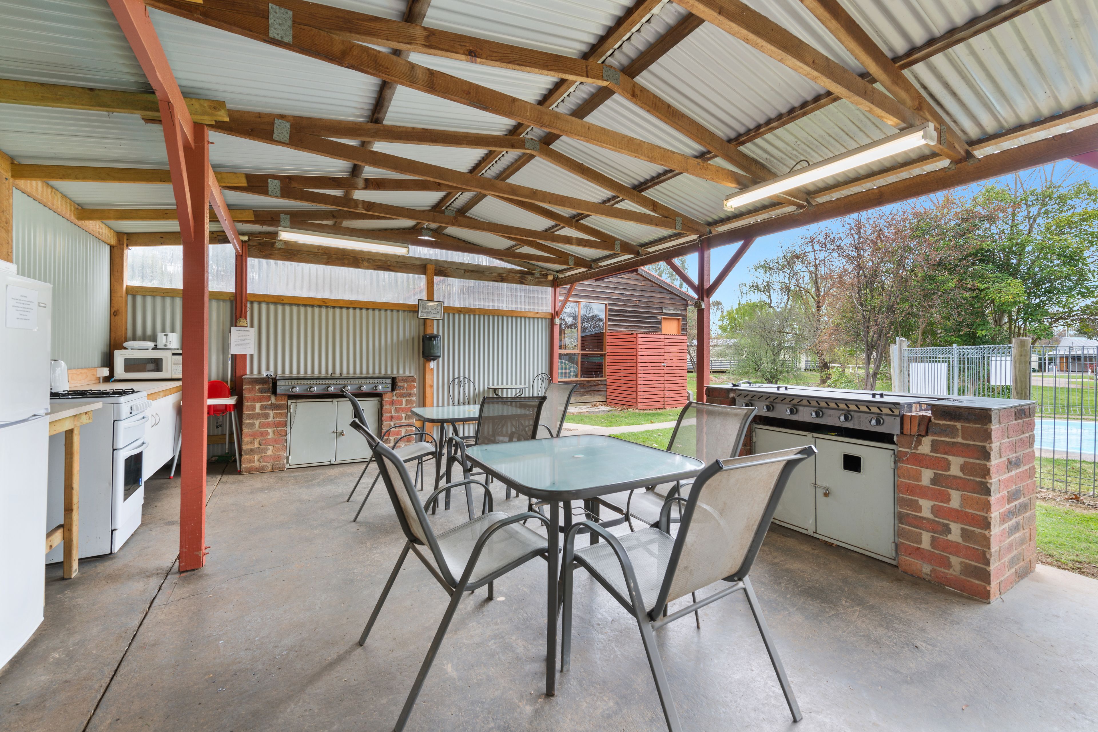 An outdoor patio with a grill, dining table, and chairs.