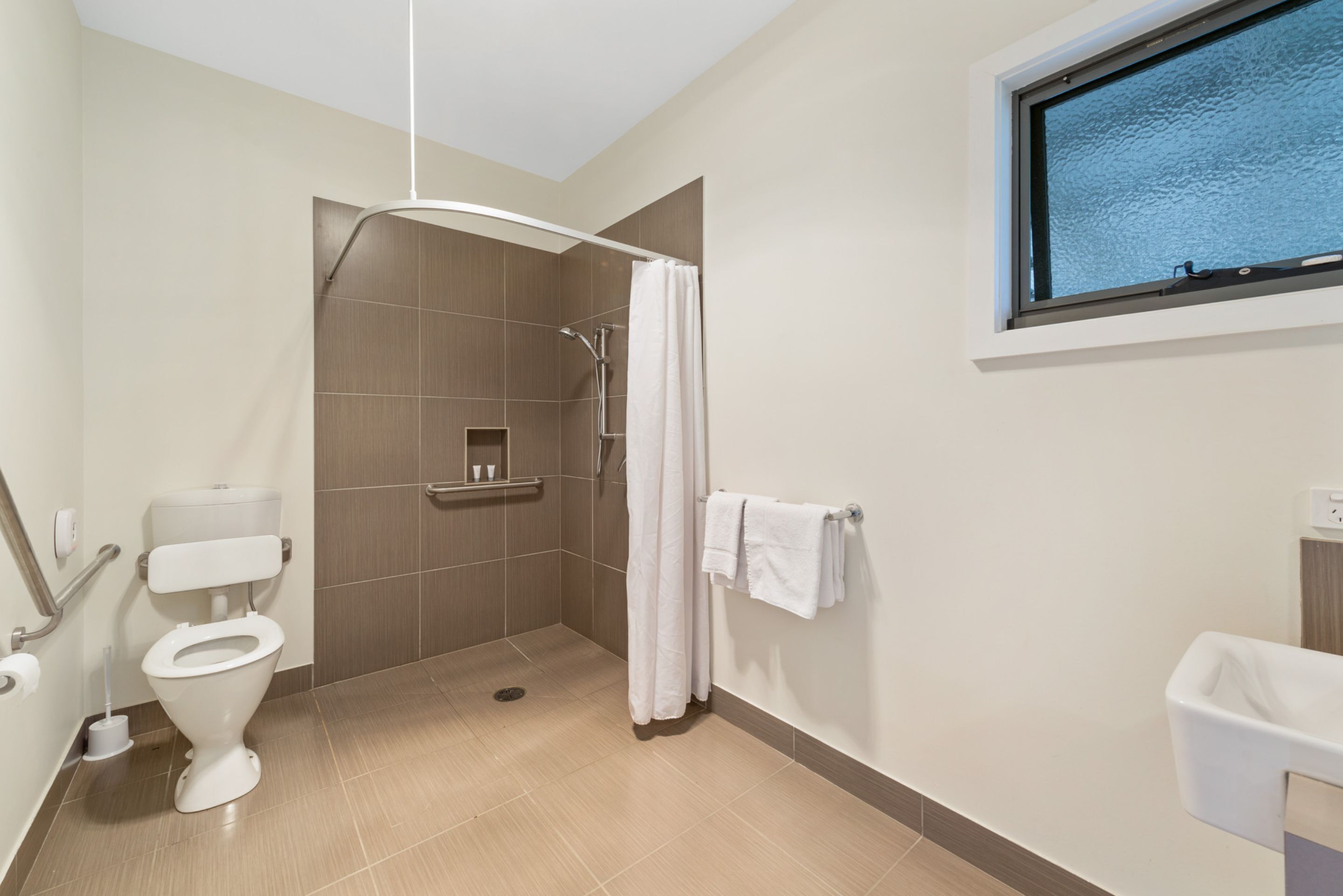 A modern bathroom with a shower, toilet, and sink.