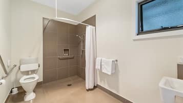 A modern bathroom with a shower, toilet, and sink.