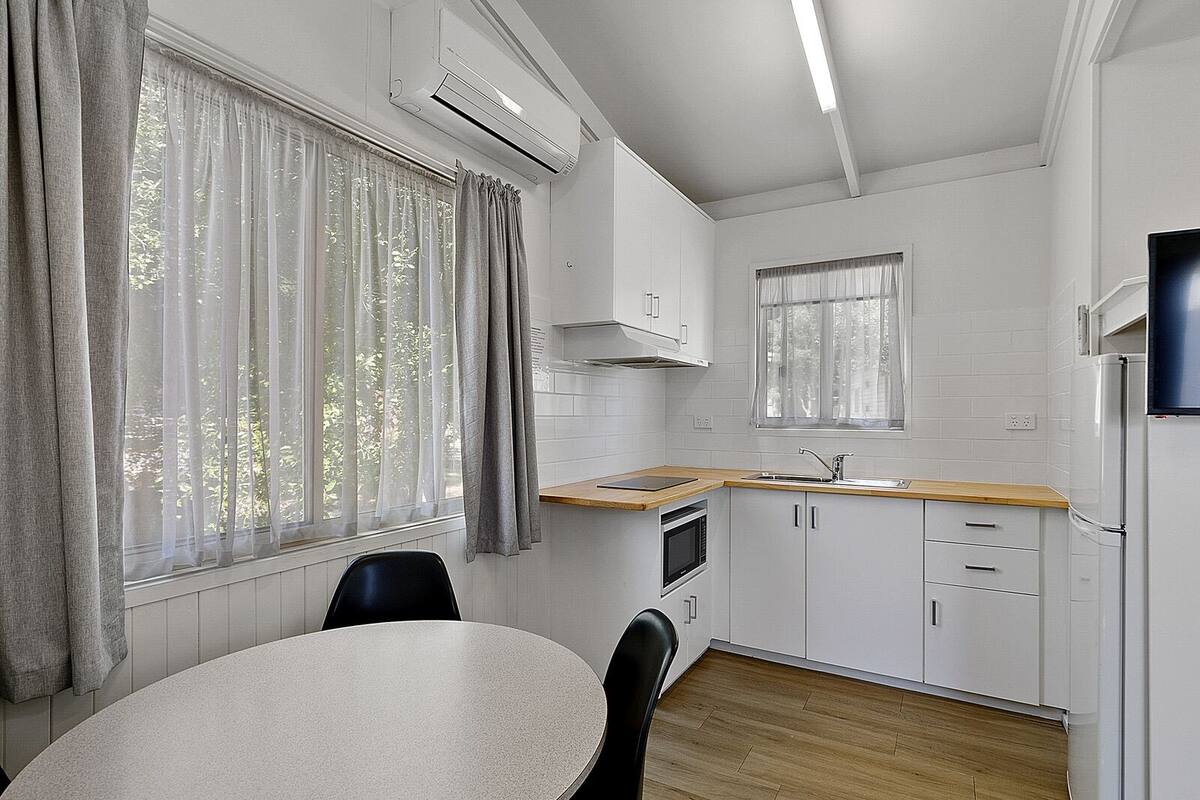 A compact kitchen with a dining area, featuring a microwave, sink, and cabinets.