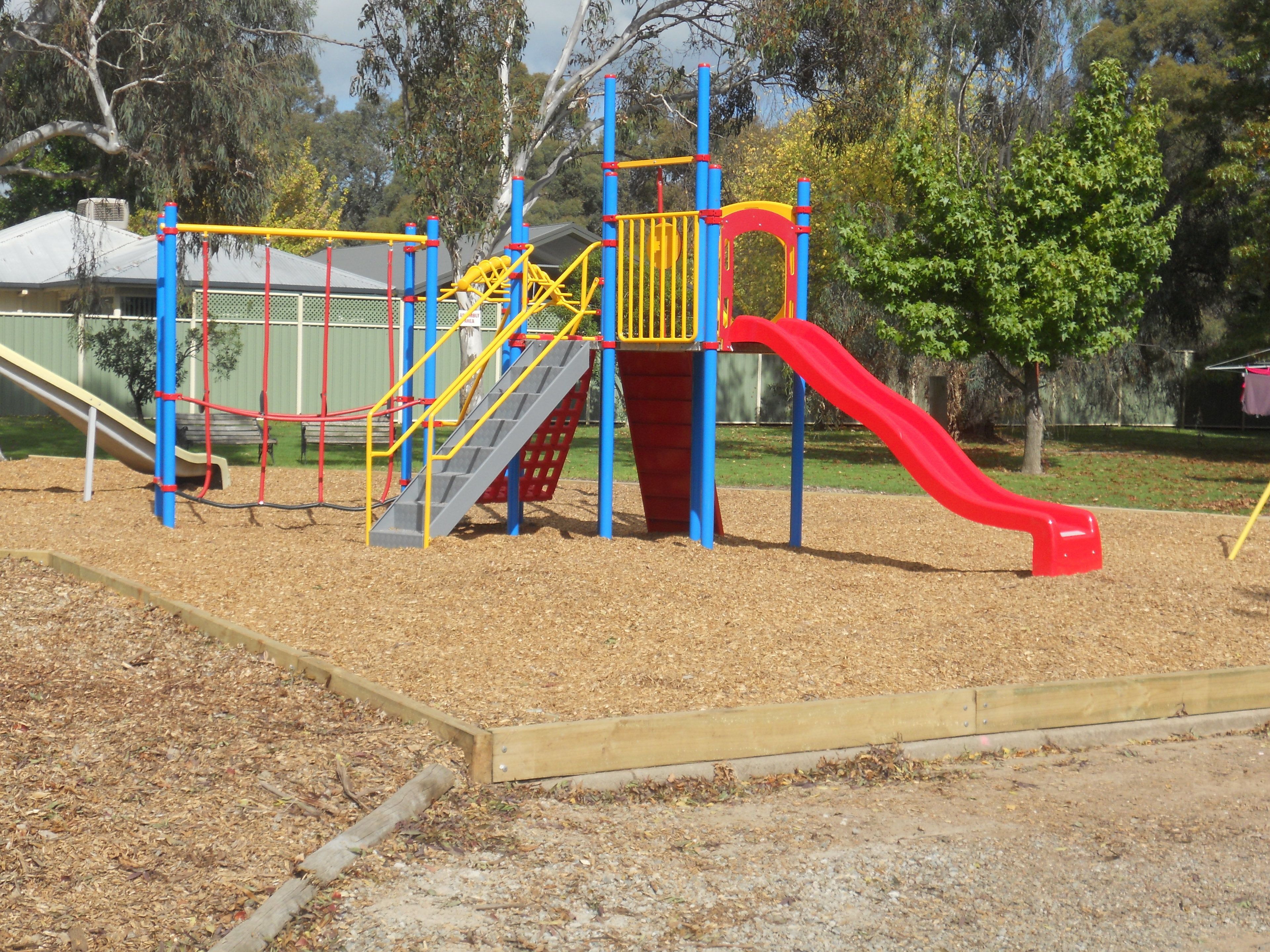 A playground with a slide, climbing structures, and a red slide.
