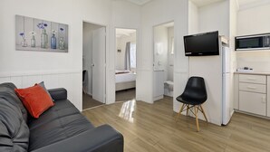A modern, well-lit room with a grey sofa, a red pillow, a black chair, a TV, and a microwave. - High Country Holiday Park (Mansfield)
