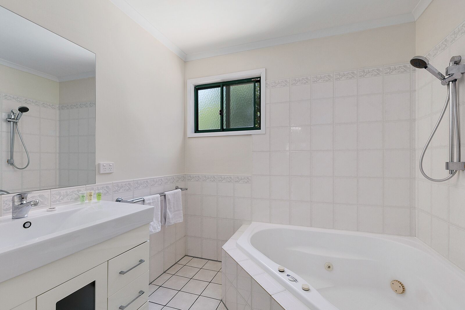 A bathroom with a bathtub, a shower, a sink with a mirror, and a window.