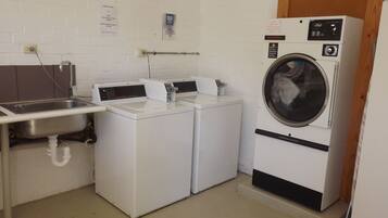 A laundry room with two front-loading washing machines, a sink, and a wooden door.